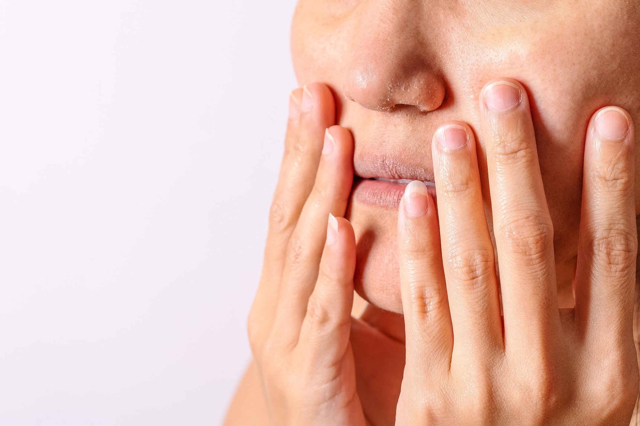 A woman, possibly suffering from xerostomia - commonly known as dry mouth - touches her face with her hands in discomfort.